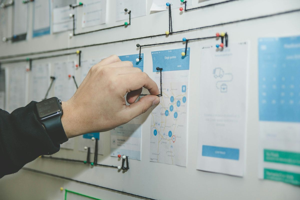 A hand pinning a printed website layout to a planning wall