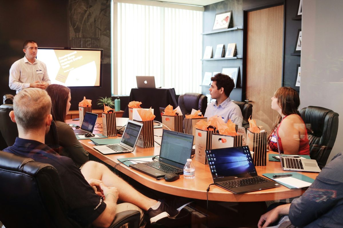 A team around a meeting table with laptops during a working session