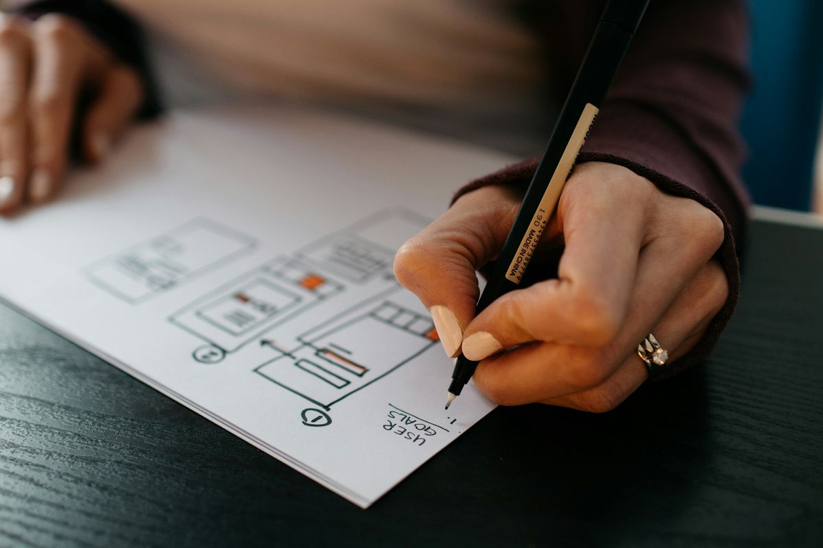 A hand sketching a website wireframe on paper