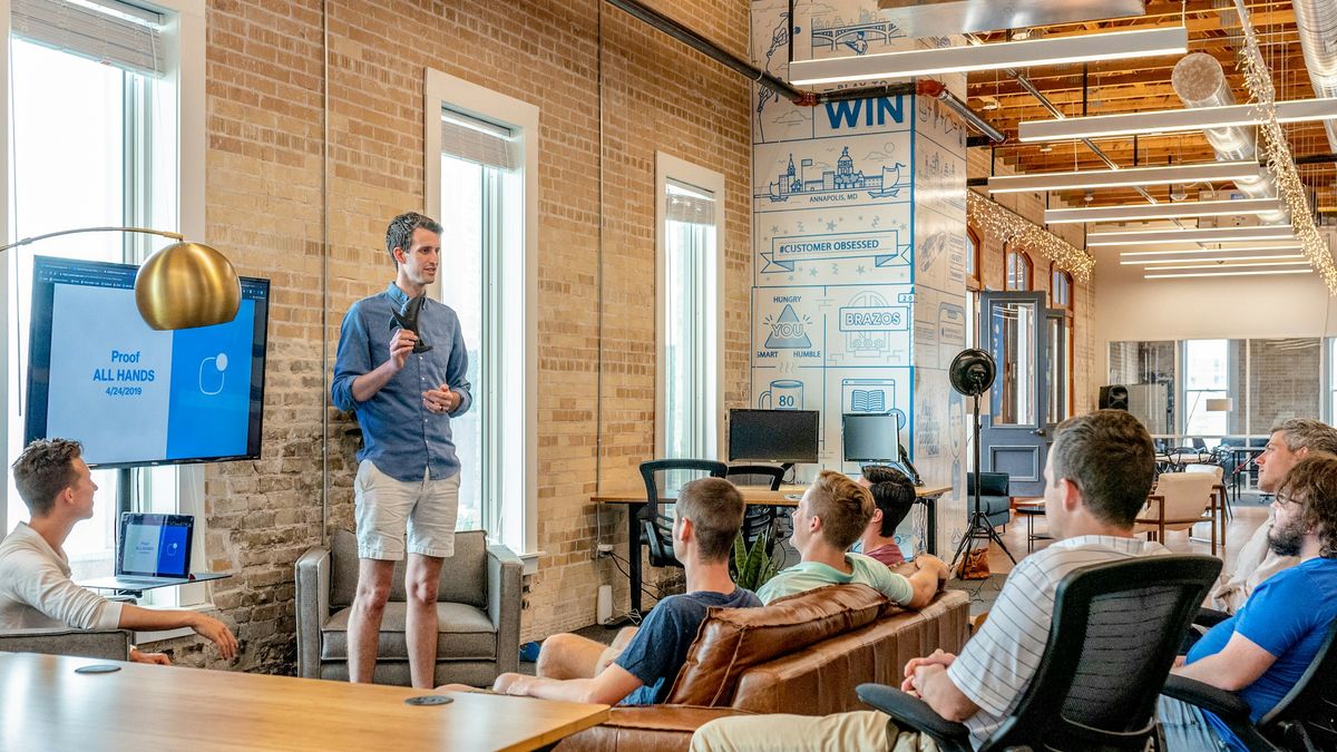 A consultant presenting to a team in a bright, brick-walled office